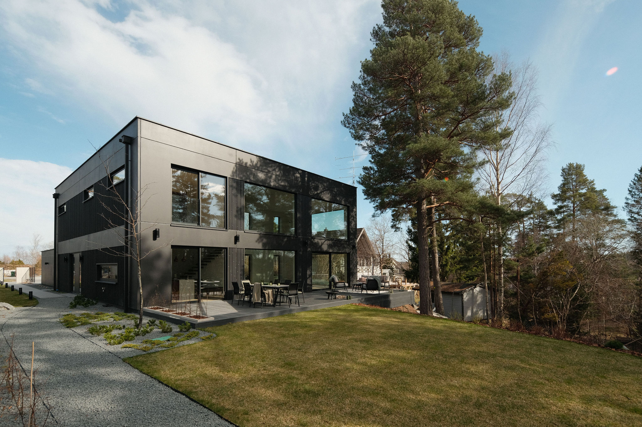 Vollständiger Baukörper der MABUDO-Villa mit verglaster Ecke vor dramatischem Himmel