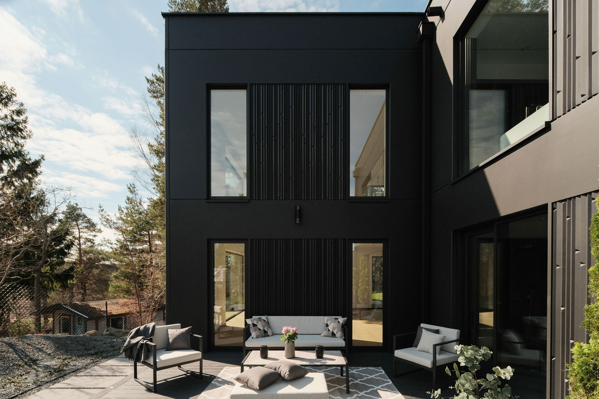 MABUDO-Villen in Åkersberga – matte anthrazitfarbene Fassade und warmes Licht im Inneren bei Dämmerung